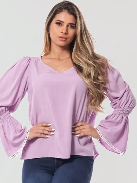 Mulher usando blusa lavanda de manga bufante com detalhe em renda, estilo casual elegante
