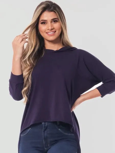 Mulher loira sorrindo usando blusa azul marinho de manga 3/4 com capuz e calça jeans