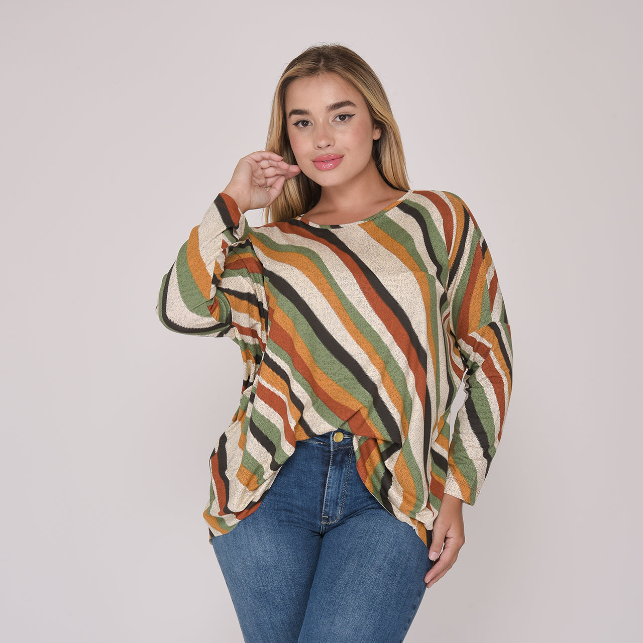 Mulher vestindo blusa listrada em tons de verde, marrom, bege e mostarda com calça jeans azul