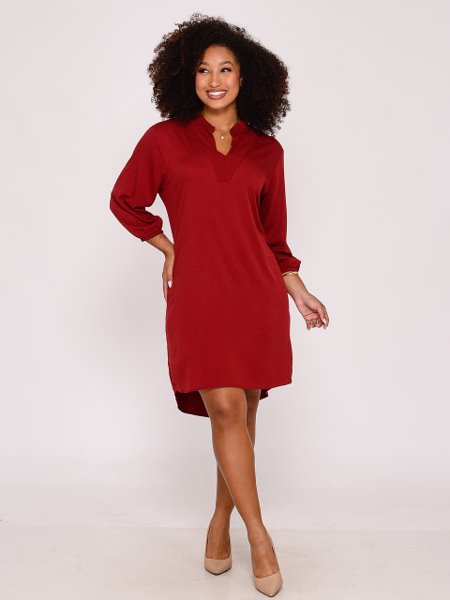 Mulher sorridente usando vestido vermelho de manga longa em estúdio com fundo branco