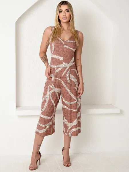 Mulher usando macacão pantacourt com estampa abstrata marrom e branco, em ambiente minimalista branco