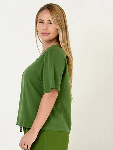 Mulher loira usando blusa verde de manga curta em fundo branco