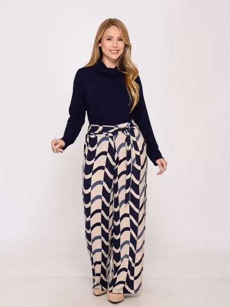 Mulher loira usando blusa preta e calça pantalona estampada com padrão ondulado azul e bege em fundo branco