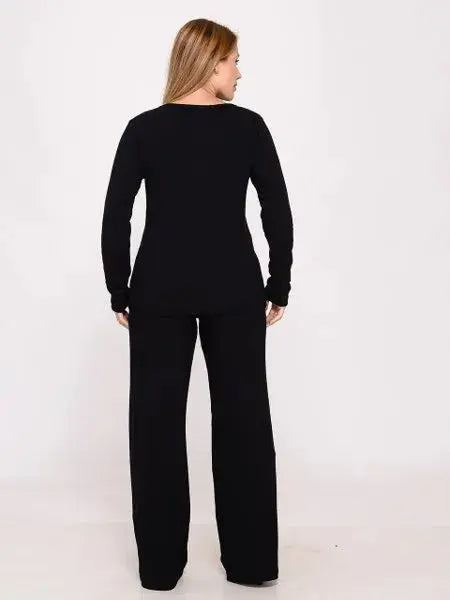 Mulher vista de costas usando conjunto preto de blusa manga longa e calça larga em fundo branco